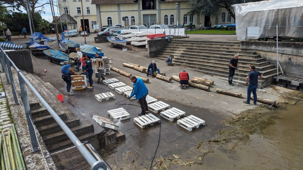 Beim Hafen-, Boots- und Hausputz. Rechts wird die Treibholzsperre montiert. Auf der Schräge werden die Deko-Paletten gesäubert.